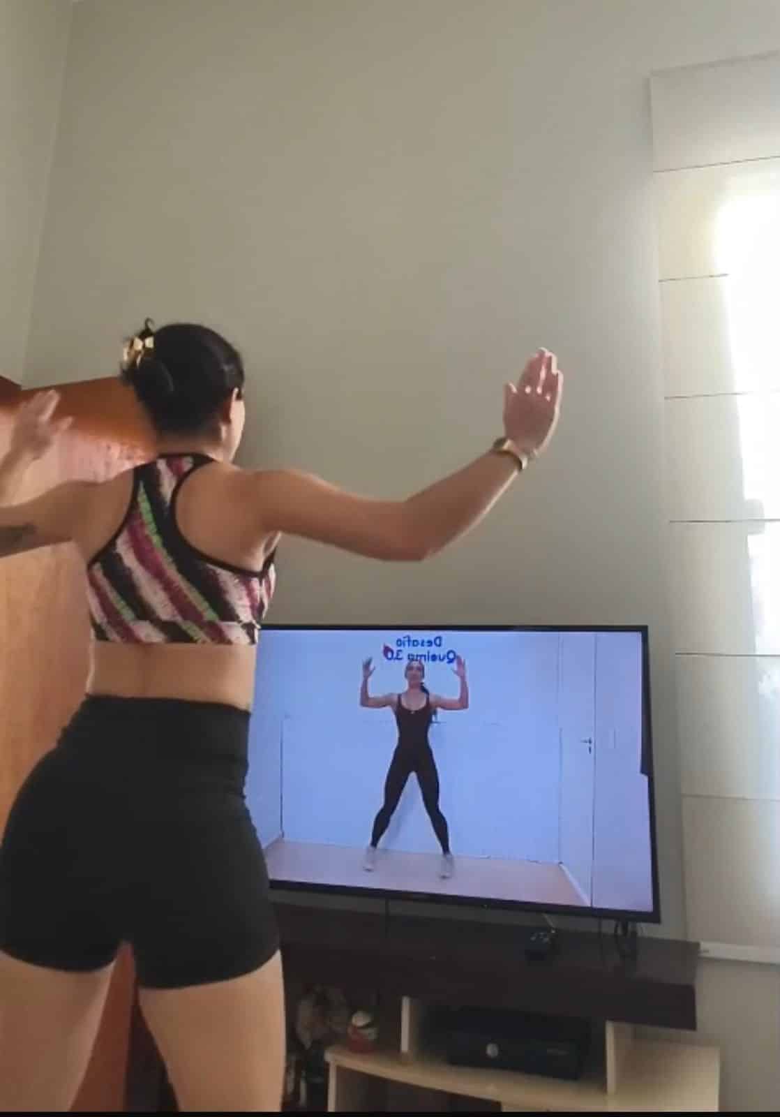 Aluna treinando em casa durante aula fitness